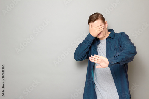 Shot of mature man is covering his face with hand protecting himself photo