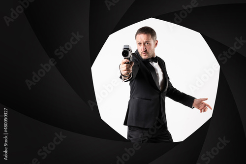 Fotografi A parody of James Bond, a man wearing a tuxedo handling a Super 8 camera in a classic 007 pose, shooting at camera