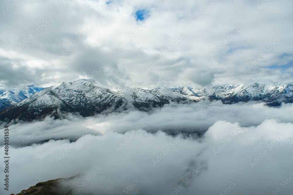 Aerial view above the clouds in snow mountain peaks valley
