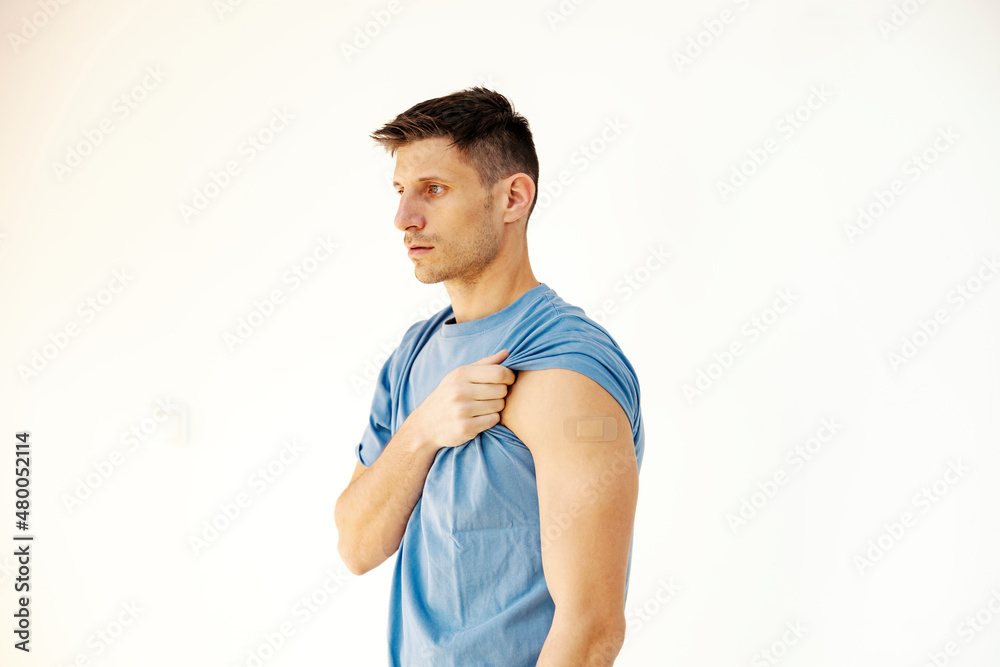 A man standing on white background and showing his arm after covid 19 vaccination. Immunization, inoculation and health care. A man standing on white background and showing his arm after covid 19 vaccination. Immunization, inoculation and health care.