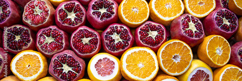 Cutted pomegranates, oranges and grapefruits on counter with street fresh juice. Red and orange fruits, front view. Real showcase with street food in Istanbul, Turkey. Web banner
