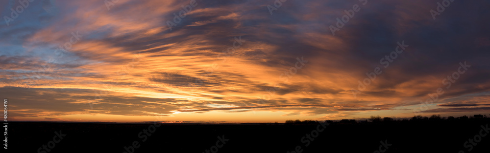 Sunset panorama with dark yellow clouds over a small town against the blue sky Sunset panorama with dark yellow clouds over a small town against the blue sky