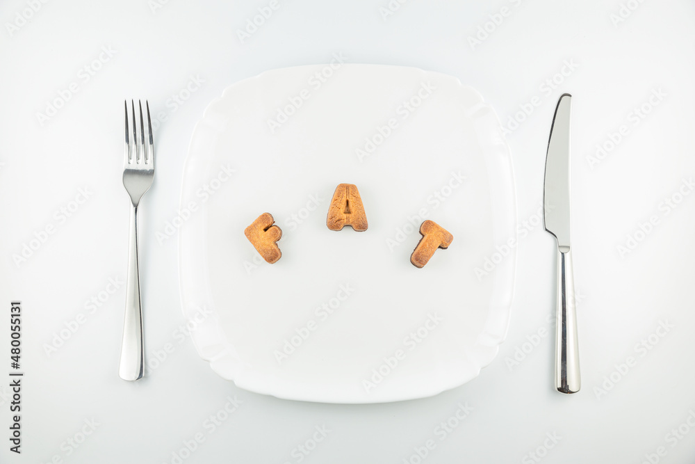 Word FAT made of cookie letters on white plate with fork and knife, low carb high fat ketogenic diet concept Word FAT made of cookie letters on white plate with fork and knife, low carb high fat ketogenic diet concept