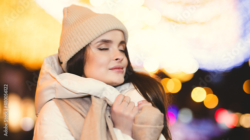 Night portrait of a girl in a winter city on a bokeh background