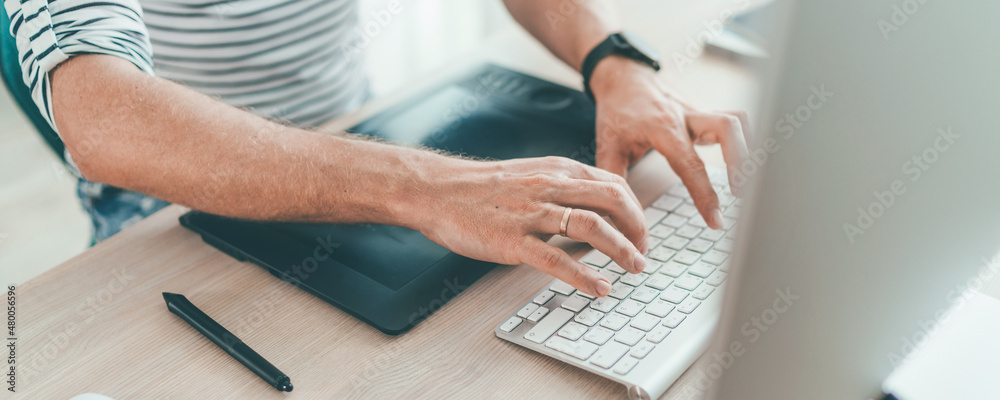 Writer typing modern computer keyboard writing novel sitting at the white wood table. Distance or freelance work on worldwide quarantine time concept