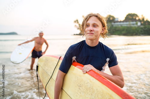 Canvas Print Portrait of a teen boy with a surfboard after surfing with his father
