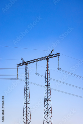 High Voltage Tower supporting an overhead power lines against blue sky