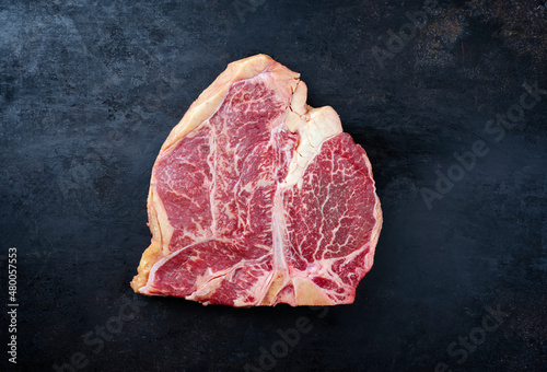 Raw dry aged wagyu porterhouse beef steak offered as close-up on rustic old board with copy space