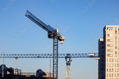 Tower cranes on the costruction site on blue sky background