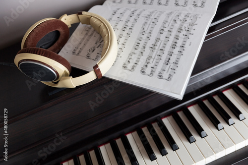 Piano keys, headphones, and sheet music blurred photo