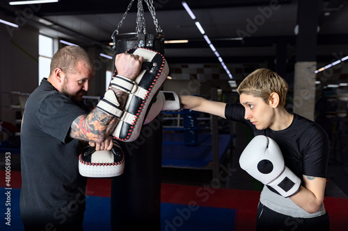 Female boxer sparring with her male coach in boxing club punching kicking pad (mitts) photo