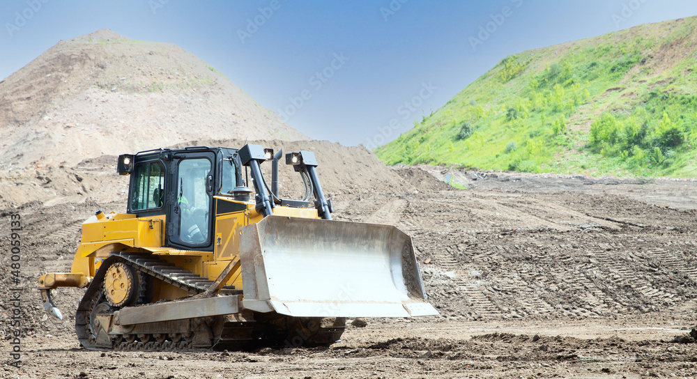 Heavy yellow bulldozer moving soil on the construction site