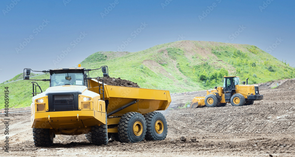 Obraz premium Wheel loader and dump truck on the construction site