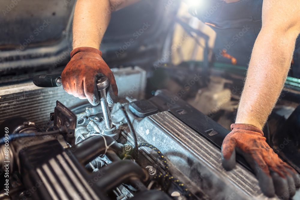 car engine repair, car mechanic tightening valve cover bolts.