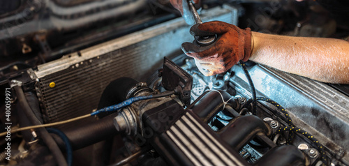 repairing a car engine in a car service, the hands of a mechanic unscrew the bolts