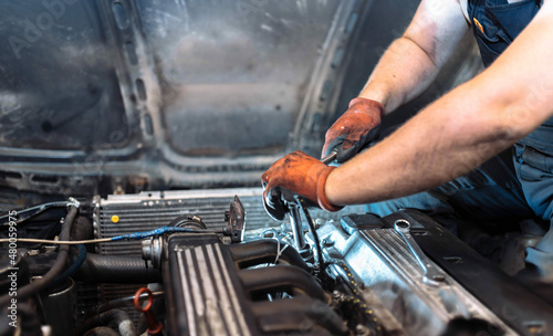 repairing a car engine in a car service, the hands of a mechanic unscrew the bolts