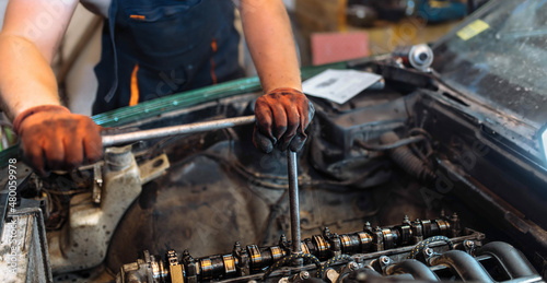 repairing a car engine in a car service, the hands of a mechanic unscrew the bolts