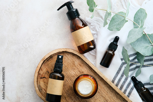 Set of natural organic SPA beauty products on wooden board with eucalyptus leaves. Amber glass cosmetic bottles top view. photo