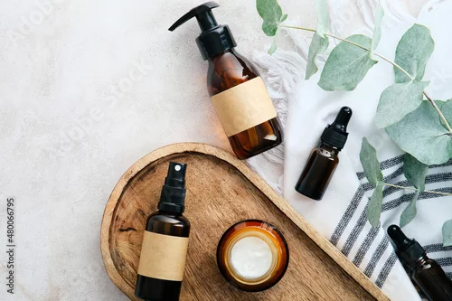 Obraz Set of natural organic SPA beauty products on wooden board with eucalyptus leaves. Amber glass cosmetic bottles top view.
