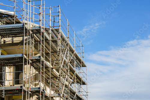 Frame of modern metal scaffolding on a building under construction on a background of blue sky.