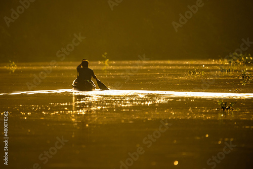 Scenic view of fisherman in canoe at sunrise on the river