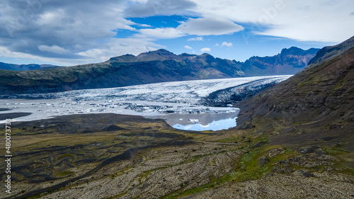Fototapeta Naklejka Na Ścianę i Meble -  Beautiful Cinematic Aerial view of the massive Svinafellsjokull Glacier in Iceland and its lagoon caused by global warming