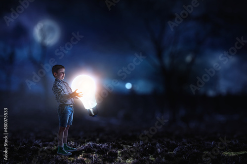 Boy standing next to a light bulb © Sergey Nivens