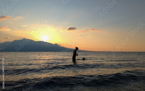 A woman playing with the dogs at the beach.