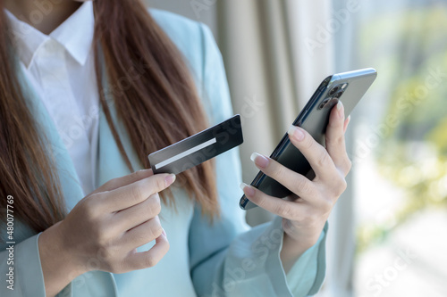 Asian woman using credit card with mobile phone for online shopping, technology money wallet and online payment concept.