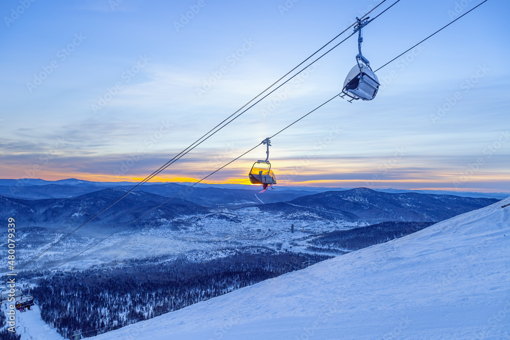 View from mount peak on Sheregesh ski resort and Altai mountains or Gornaya Shoria. Active winter rest, skiers and snowboarders on ski slope and Ski lift, nature and sport leisure.