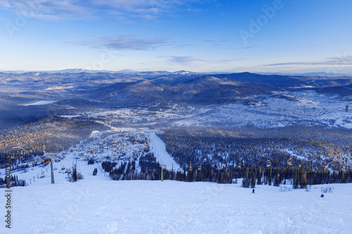 View from mount peak on Sheregesh ski resort and Altai mountains or Gornaya Shoria. Active winter rest, skiers and snowboarders on ski slope and Ski lift, nature and sport leisure.