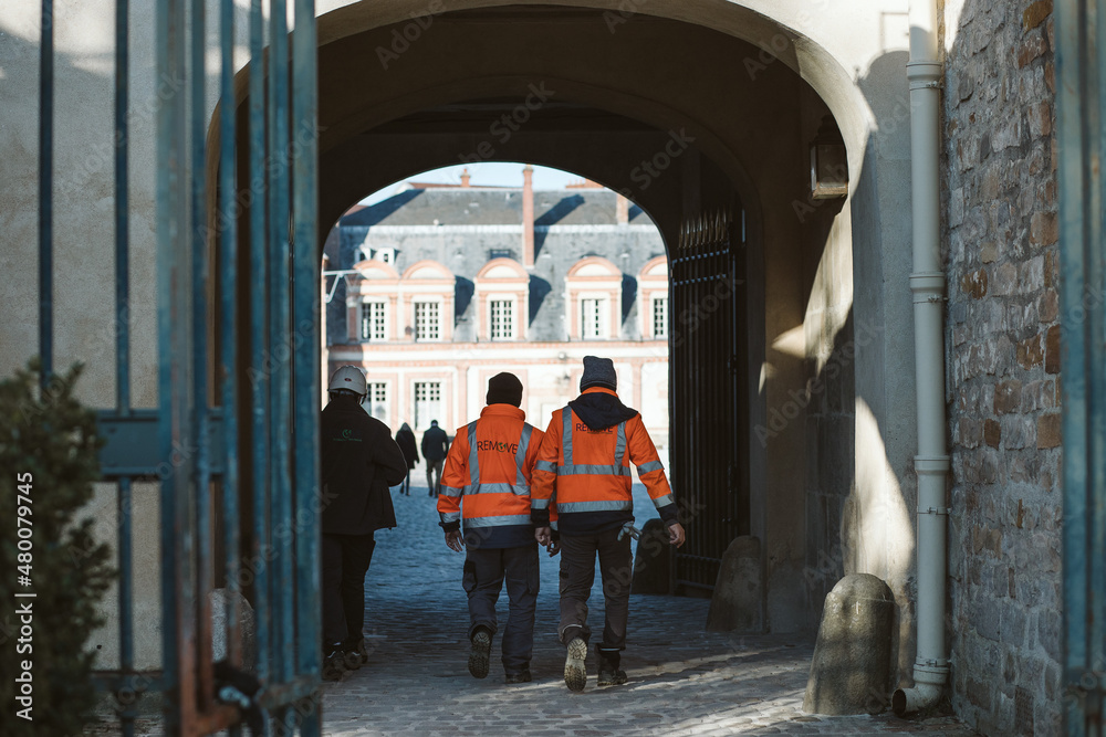 men and security guard walking in orange safety vest in a castle and on the street 