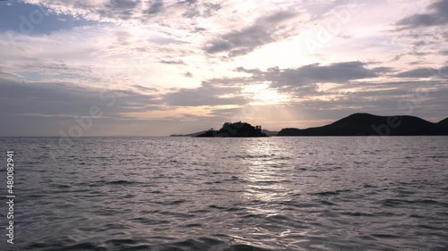 Wave on sea water with a mountain and cloudy sky background at sunset