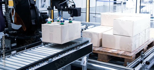 Smart logistic industry. Industrial autonomous robot loading carton on conveyor in smart warehouse system.