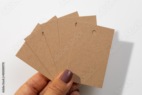 Bunch of blank cardboard rectangular label tags for clothes looking together like fan with tiny hole in upper part in center with shadows falling on white background. Tag mock up. Copy space.