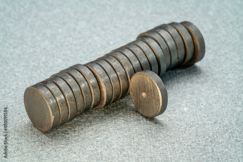 Foto stack of small round ceramic ferrite magnets on textured gray  paper
