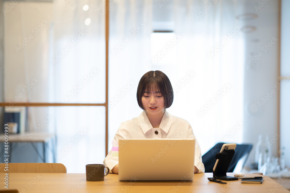 自宅の部屋でノートPCを操作する若い女性 自宅の部屋でノートPCを操作する若い女性