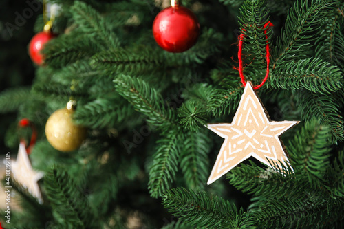 Star made of cardboard hanging on Christmas tree, closeup