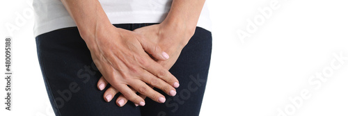 Young sick woman holds hands pressing to perineum to lower abdomen photo
