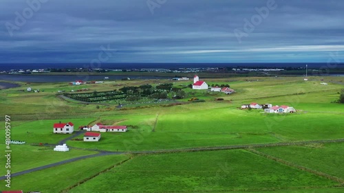 Typical Houses With Church And Cemetery Surrounded With Green Grassland In Gardakirkjugardur, Gardabaer, Iceland. - aerial photo