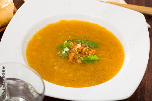 Dietary cream soup of vegetables garnished with caramelized onion and fresh arugula ..