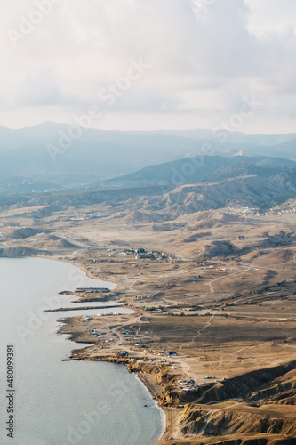 Crimea, Cape Meganom. view from the hill to the sea and the village in brown and blue tones. Evening