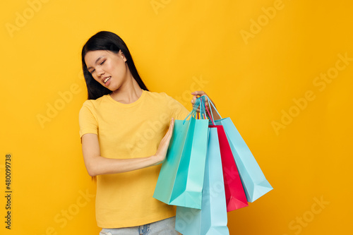 Portrait Asian beautiful young woman in a yellow T-shirt with multicolored shopping bags studio model unaltered