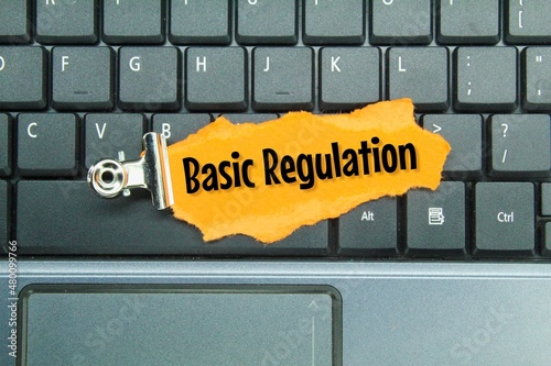 laptop keyboards and torn colored paper with the words basic regulation photo
