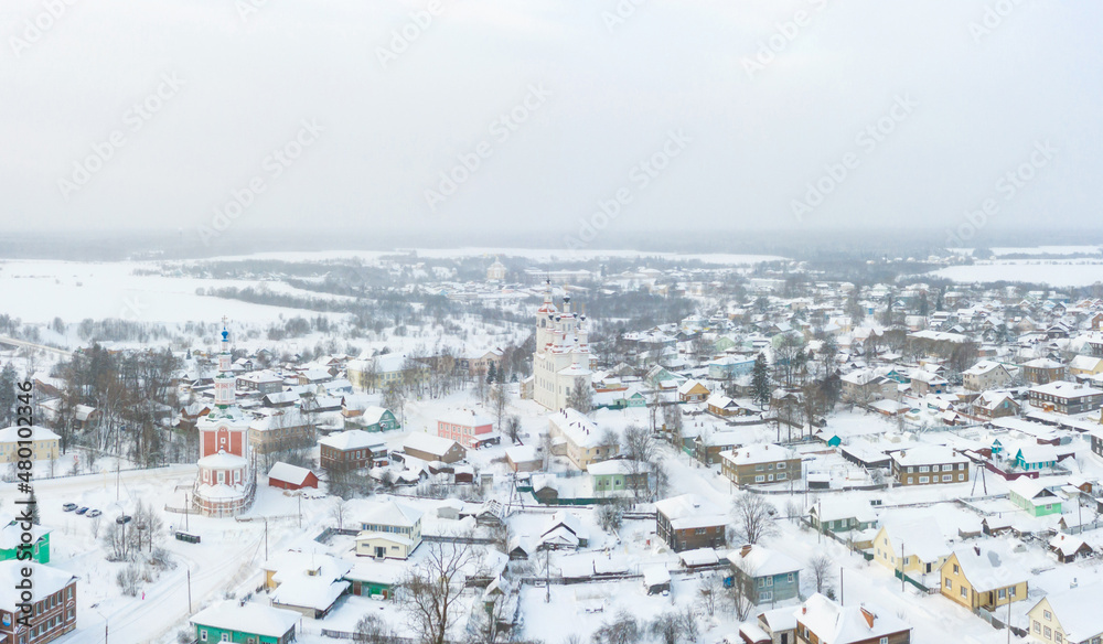 Panorama of a small city in the depths of Russia from a height. Orthodox churches and traditional old wooden houses, Totma in the Vologda region and a winter view of the city