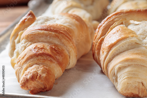 Close-up view of homemade croissants on a baking paper. Selective focus. © mihrzn