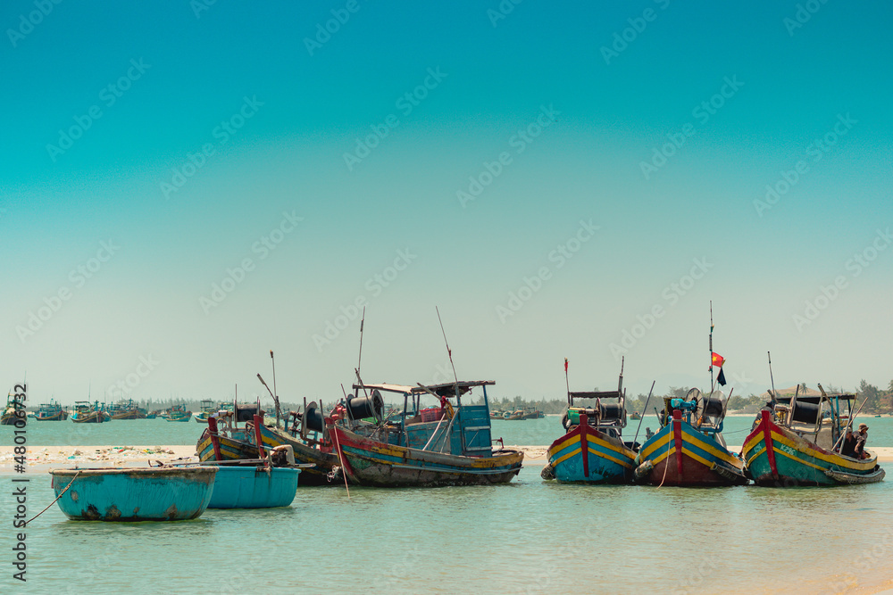Aquamarine azure seascape clear sky view. Real nature beauty background. Red blue motor boats sail docked shallow water edge sand beach bay calm sea. Fishing life style. Paradise, trip leisure travel