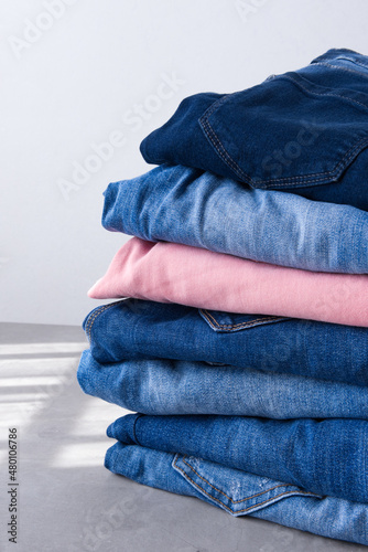 a pile of blue and pink jeans on a gray background. Close up (ID: 480106786)