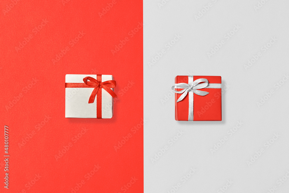 Exchange of gifts. Gift boxes of white and red color on paper surfaces of white and red color. Top view.