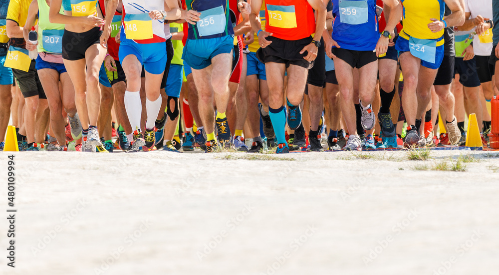 Obraz premium Large group of sportsmen starting running contest at desert.